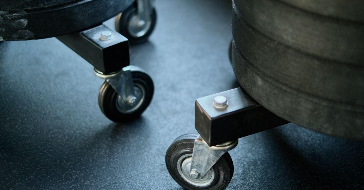 Wheels of gym equipment close-up on a black gym floor, showcasing industrial design.